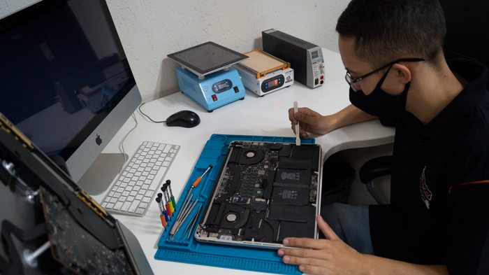 Profissional da Fixnow trabalhando em um notebook na bancada da loja